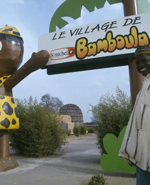 Un artisan ivoirien posant devant le village de Bamboula