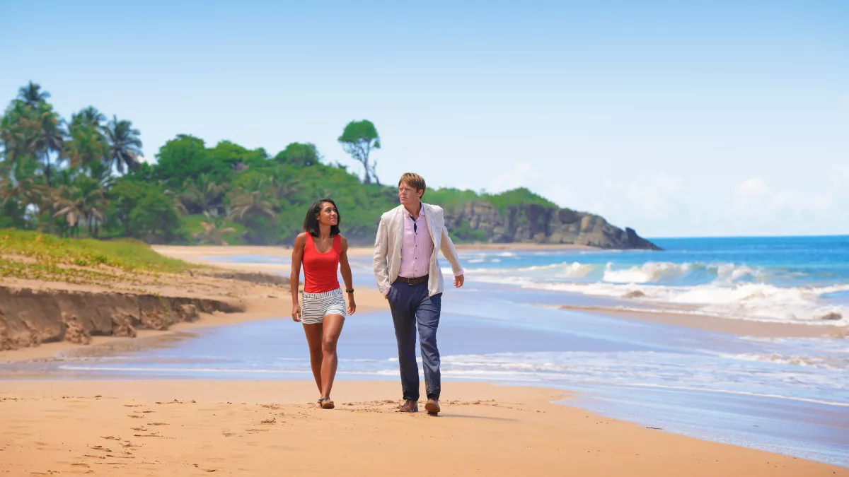 Copyright Red Planet Productions / Joséphine Jobert et Kris Marshall Photo de Joséphine Jobert et Kris Marshall marchant sur une plage, dans Meurtres au paradis