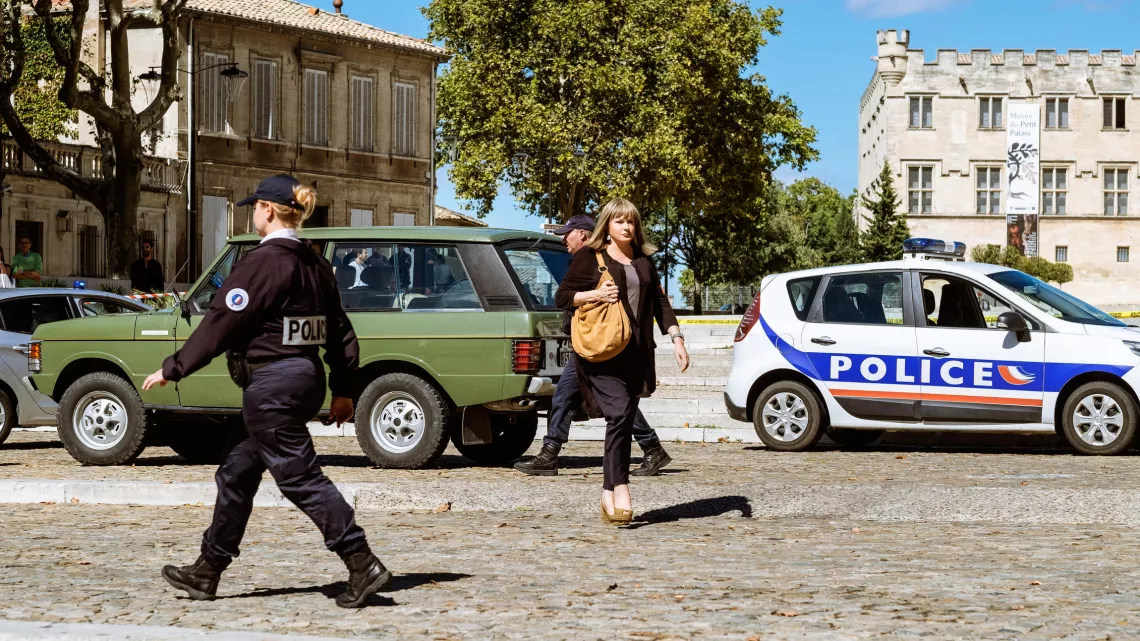 Catherine Jacob (le commandant Laurence Ravel) traverse la route à côté d'une voiture de police